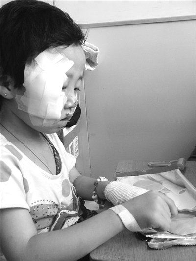 昨天下午，台湖卫生院病房内，妞妞正在玩橡皮泥。两颊的颧骨部位均用纱布包裹。