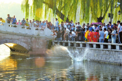 北京什刹海百余斤鱼放生时遭哄抢 两围观者落水