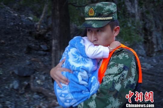 图为新疆博乐市一名消防人员抱着孩子走出森林公园。 袁祥建 摄 图为新疆博乐市一名消防人员抱着孩子走出森林公园。 袁祥建 摄